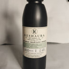 A dark bottle of Keshaura Herbal Hair Fall Oil with a cream colored label, photographed against a neutral gray background. Keshaura Anti Hairfall Hair Oil.